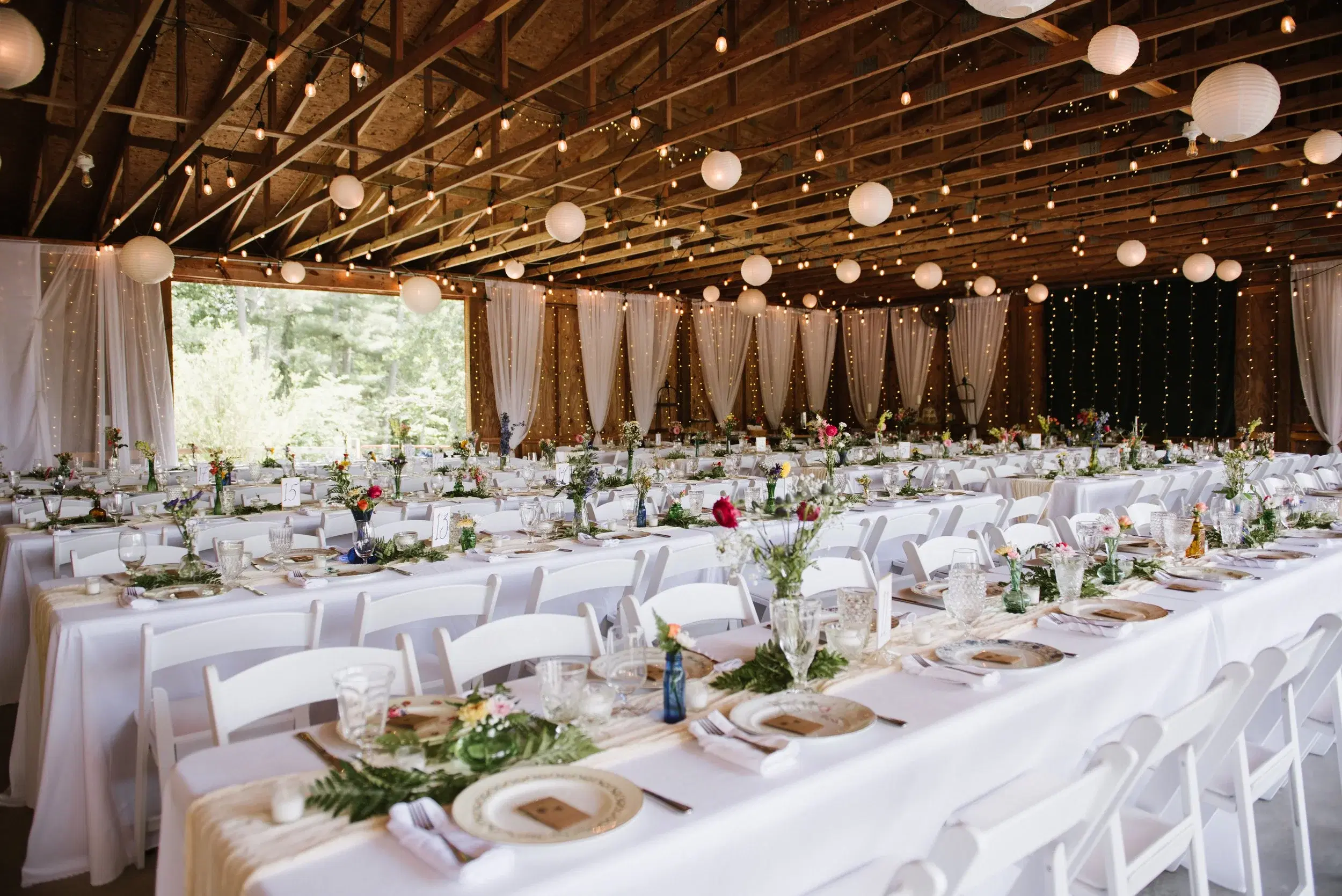Emerald Ridge Farm wedding reception barn interior with long tables and paper lanterns